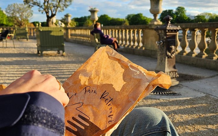 A paper bakery bag held on a lap in a Paris park